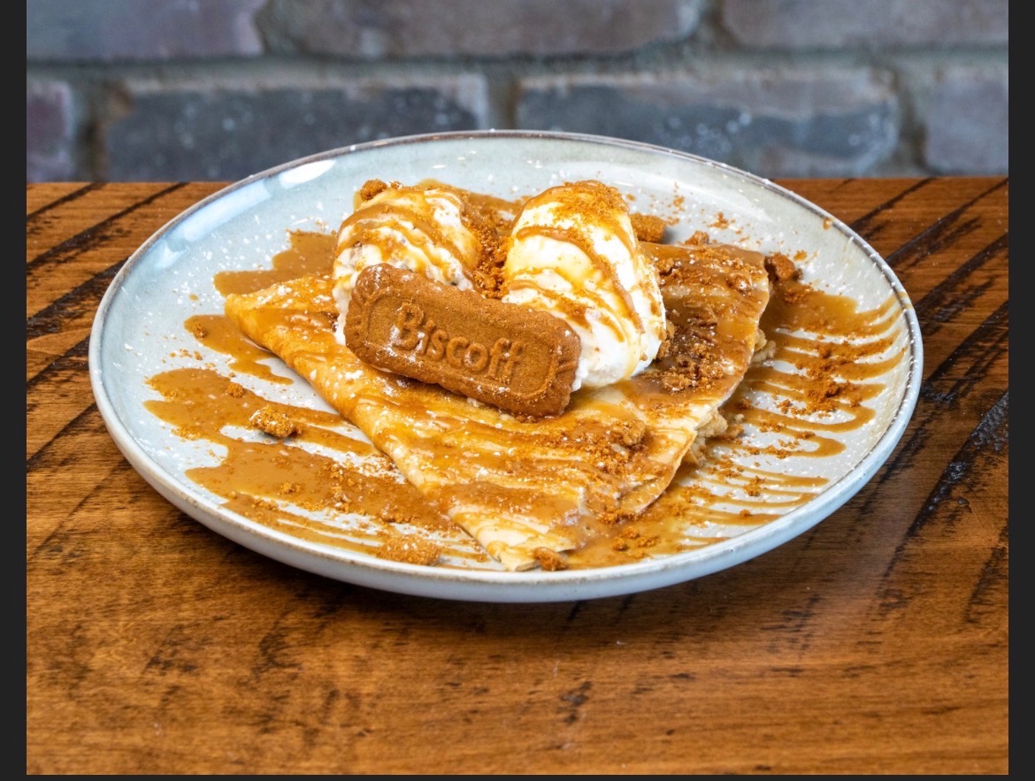 Folded crepe topped with ice cream, a Lotus Biscoff cookie and caramel drizzle