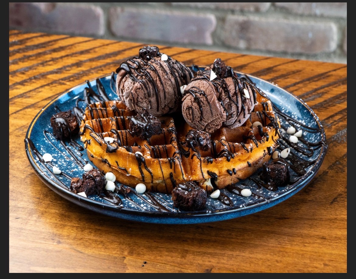 Chocolate waffle topped with chocolate ice cream, brownie bites and white chocolate chips