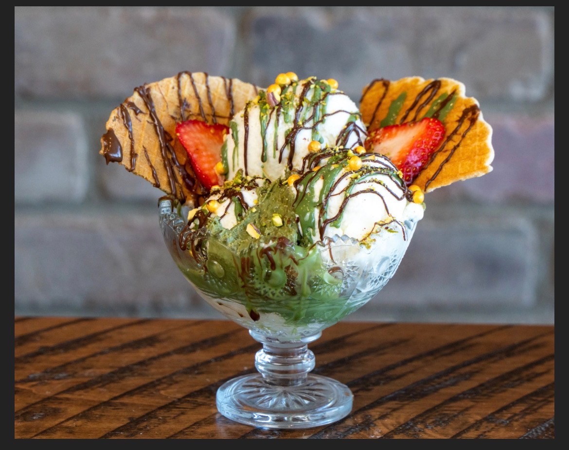 Sundae in a glass with vanilla ice cream, matcha drizzle, waffle wafers and strawberries