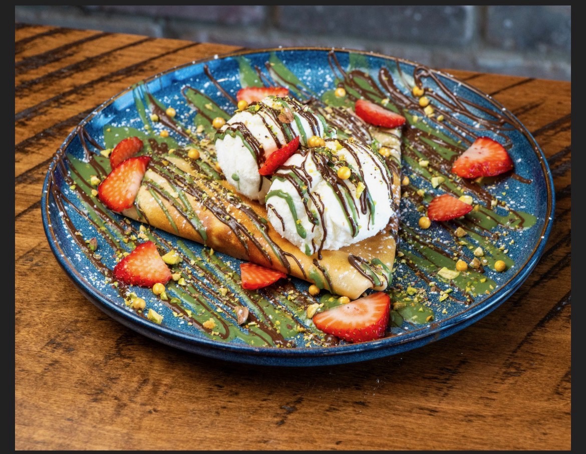 Crepe with vanilla ice cream, fresh strawberries, pistachio and chocolate drizzle